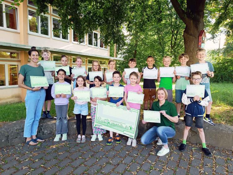 Die Schülerinnen und Schüler der Klasse 3c der Grundschule Hennen freuen sich sehr über die Überraschung. v.l.n.r. Frau Schulze, Klassenlehrerin, Schülerinnen und Schüler der Klasse 3c der Grundschule Hennen, Frau Hohmann-Stock, Stadtwerke Iserlohn